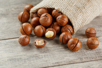 Macadamia nut on a wooden table in a bag, closeup, top view