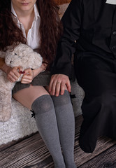 priest is holding his hand on the lap of a young girl