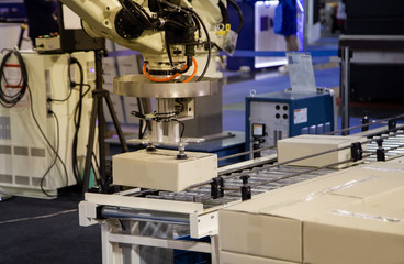 Industrial robot loading cardboard on conveyor in manufacturing production line