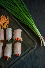 Homemade rolls with fresh chicken breast with greens, carrot slices, bell pepper on a dark cutting board. The concept of healthy homemade food. Dark wooden background.