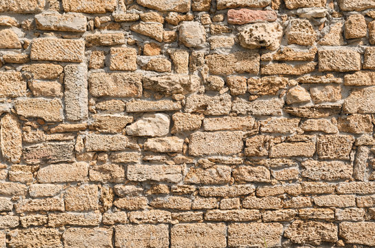 Old wall laid out in a chaotic manner of porous lime brick