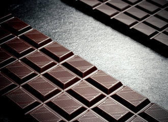 Black chocolate bar on black slate plate