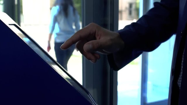 A man takes a ticket to the queue at the clinic. Hand of the man in the suit using terminal close up. The man touching the screan with his finger. Servise of the client