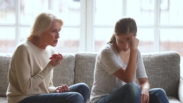 Stubborn annoyed young daughter ignoring worried stressed old mother arguing