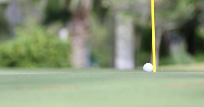 A putted ball rolls through the frame to the flagstick, and drops in the hole. Features the putter in foreground blurred to obscure trademarks or logos.