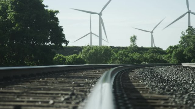 windmills blowing in background of railroad tracks