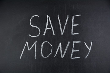 Save Money written on black chalkboard