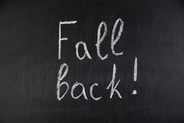 Obraz premium Fall Back written in white chalk on a black chalkboard