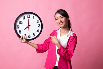 Young Asian woman point to a clock.