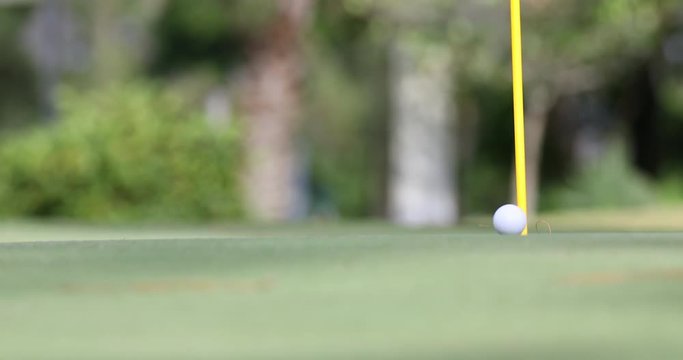 A putted ball rolls through the frame to the flagstick, and drops in the hole. Features the putter in foreground blurred to obscure trademarks or logos.