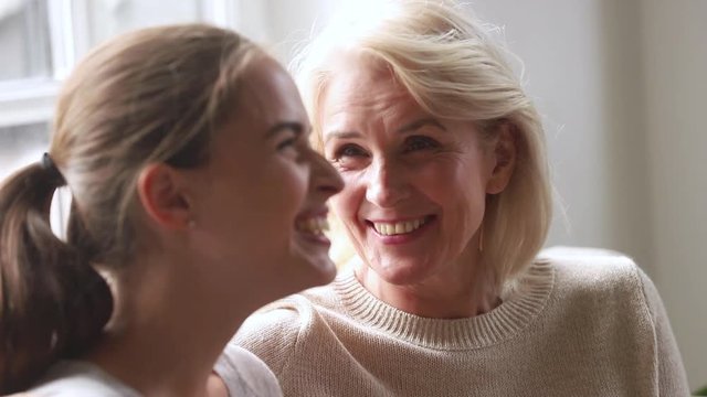 Happy old mother talking to adult daughter sharing news gossiping