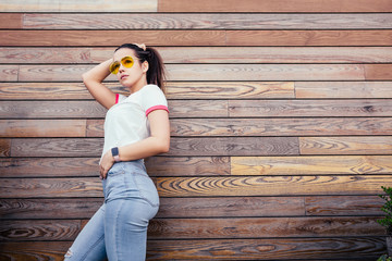 Beautiful young girl fitess blogger posing against the backdrop of a wooden fence during a trip to a warm country during the summer holidays. Copyspace