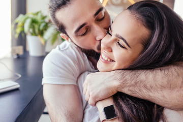 Tender young beautiful couple caring man and charming girl hug warm sit at a table in a cafe with a cup of coffee. Concept of express love and truthful feelings
