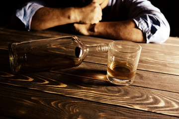 Alcoholic addict. Man near the table with empty bottle and a glass. Dangerous habit. Unhealthy life concept. Social problem.