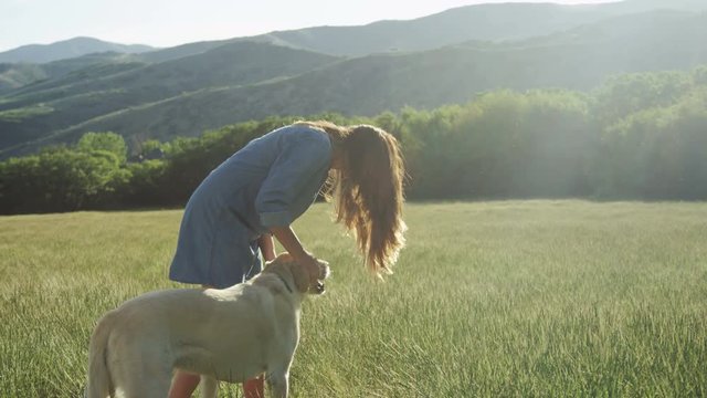 girl standing in field petting her dog