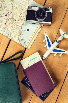 Composici&oacute;n de viaje junto a un avi&oacute;n, billetes a&eacute;reos, pasaporte, mapa, c&aacute;mara de fotos sobre un fondo de madera r&uacute;stico. Vista superior. Concepto: Viaje