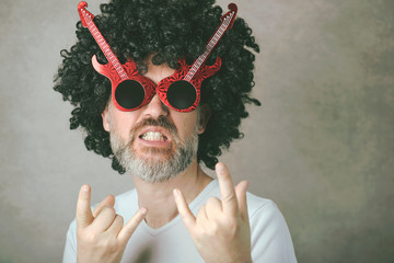 funny mature man with sunglasses doing rock symbol with hands up