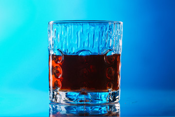 Whisky on lowball glass with ice over reflective surface
