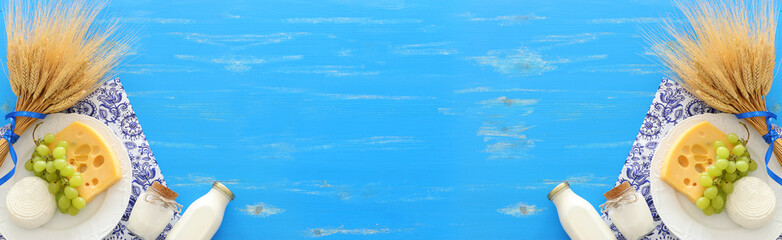 top view photo of dairy products over blue wooden background. Symbols of jewish holiday - Shavuot