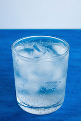  Transparent glass with water and ice cubes on a blue background