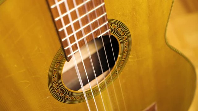 Slow motion close up of strings on acoustic guitar vibrating