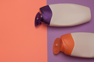Beauty, decorative cosmetics bottles. Peach and purple colors background, flat lay, top view, minimalistic pop-art style