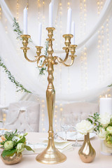 Beautiful Baroque style golden candelabra candlestick with five scalloped bobeche and white wax candles, a table centerpiece of perfect timeless elegance, setting for a banquet or a wedding reception