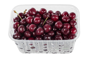 Harvest red sweet cherries in transparent plastic container isolated on white background.