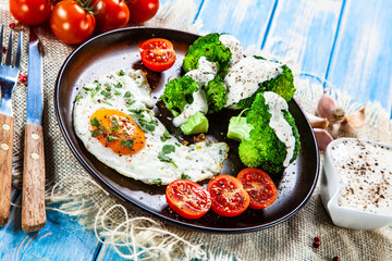 Fried egg with vegetables on wooden table