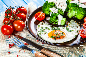 Fried egg with vegetables on wooden table