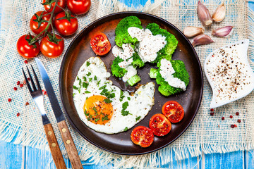 Fried egg with vegetables on wooden table