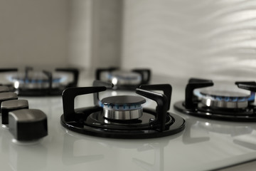 Gas burners with blue flame on modern stove, closeup