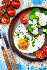 Fried egg with vegetables on wooden table