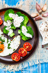 Fried egg with vegetables on wooden table