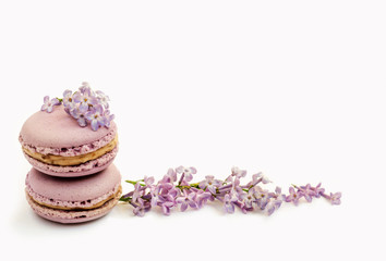 Obraz na płótnie Canvas Tasty french macaroons and lilac flowers on a white background