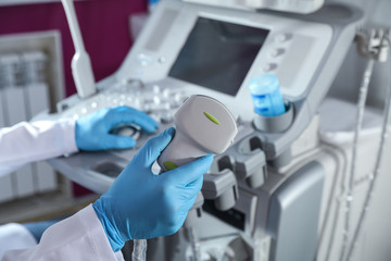 Sonographer holding ultrasound machine probe in clinic, closeup