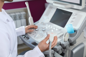 Sonographer using modern ultrasound machine in clinic, closeup