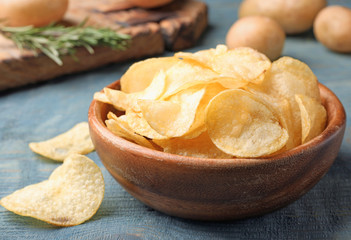 Obraz na płótnie Canvas Bowl of crispy potato chips on wooden table