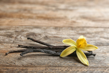 Vanilla sticks and flower on wooden background. Space for text