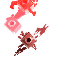 Spilled different nail polishes with bottles on white background, top view