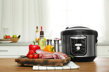 Modern multi cooker and products on wooden table in kitchen. Space for text