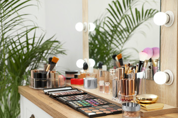 Set of luxury makeup products and accessories on dressing table with mirror. Space for text