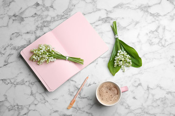 Flat lay composition with notebook, lily of the valley bouquets and coffee on marble background. Space for text