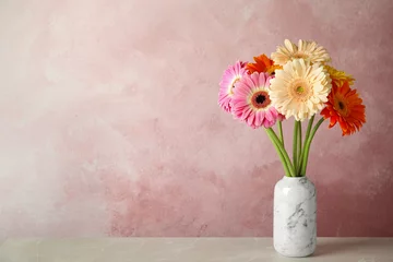 Selbstklebende Fototapeten Blumenstrauß aus schönen hellen Gerbera-Blumen in Vase auf Marmortisch vor farbigem Hintergrund. Platz für Text © New Africa