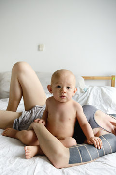 A young boy sits up in bed with his mom holding him