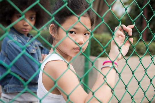 Cool girl looking thought the fence in a park