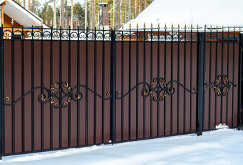 beautiful wrought iron fence with a gate on the private sector in a country house in winter snow
