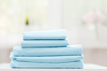 On the table is a stack of blue bedding on a blurred background.