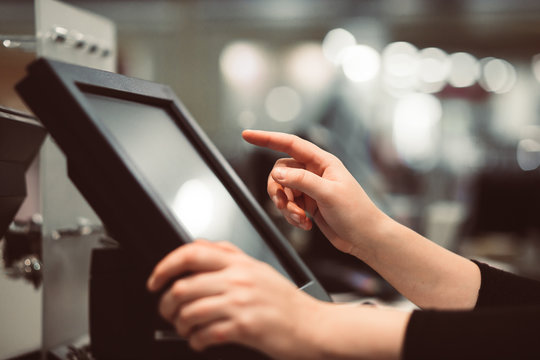 Young woman hand doing process payment on a touchscreen cash register, finance concept (color toned image)