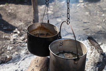 Cooking in two sooty old cauldrons on campfire